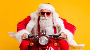 Stock image of a man dressed as Santa riding a red motorbike.